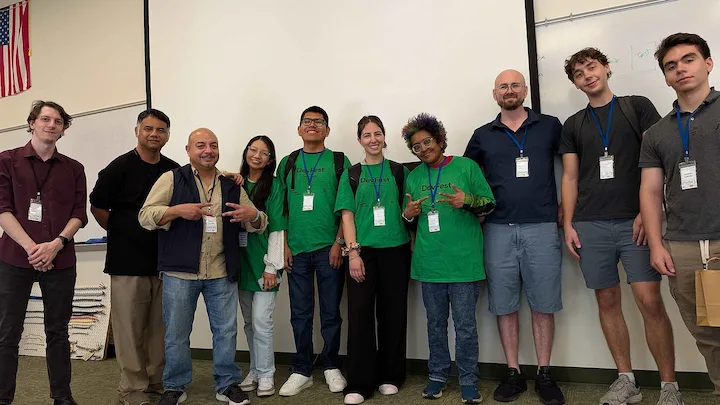 Hackathon participants, mentors, and organizers posing together in front of a whiteboard at a DevFest Florida Hackathon